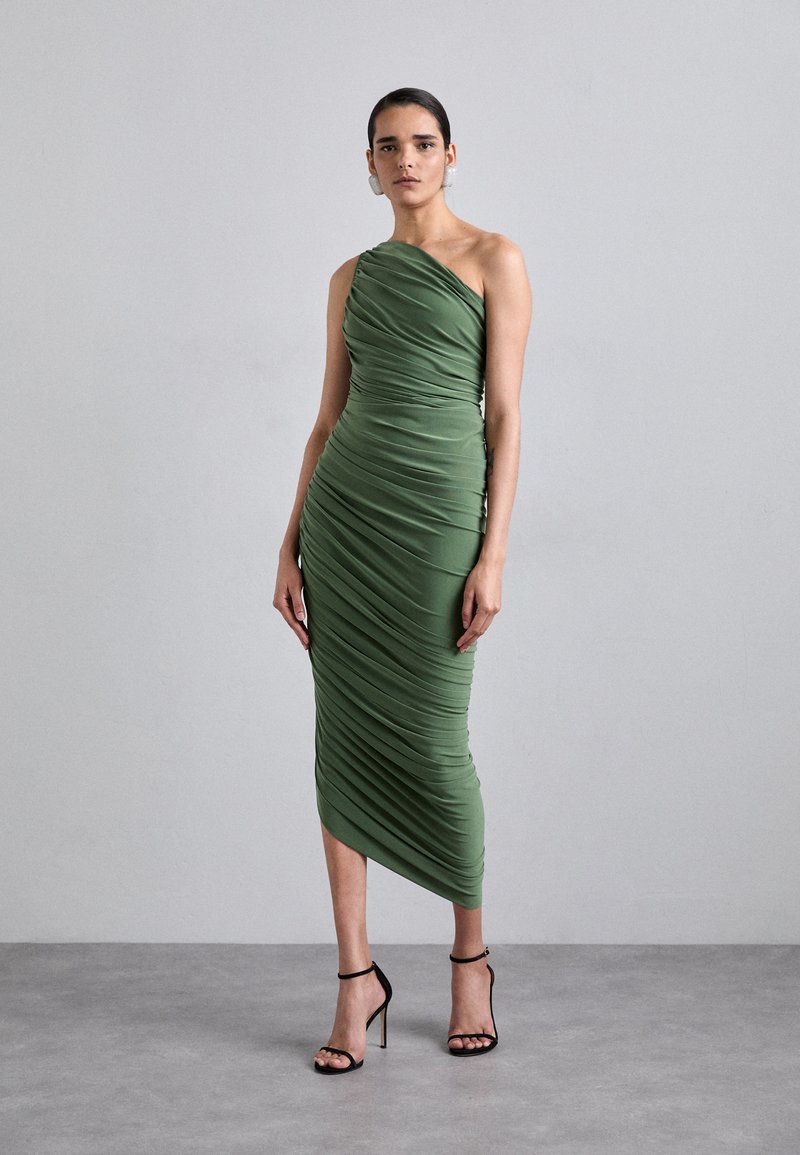 Green, one-shoulder dress made of gathered fabric, knee-length, with a ruched texture. Paired with black high-heeled sandals.