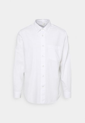 Camisa blanca de manga larga en una tela suave, con un cuello clásico, cierre de botones en la parte delantera y un bolsillo en el pecho. Textura lisa, corte relajado.