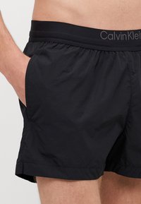 Pantaloncini da nuoto neri realizzati in materiale leggero, con vita elasticizzata e logo Calvin Klein, tasche laterali e vestibilità rilassata.