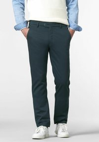 Donkergroene chino's van soepel katoen, met een slim fit, zijzakken en een knoopsluiting, gecombineerd met witte sneakers en een lichte top.