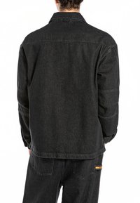 Zwarte denim jas met een rechte snit, zichtbare stiksels en een klassieke kraag. Heeft een rugstuk en een minimalistisch ontwerp zonder versieringen.