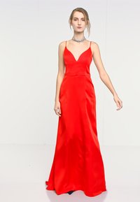 Abito da sera in satin rosso con scollatura a V e spalline sottili, silhouette fluida e texture liscia. Presenta una vita aderente e un design lungo fino al pavimento.