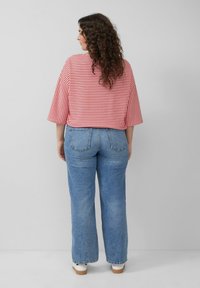 Rood-wit gestreepte crop top met brede mouwen, gecombineerd met lichtblauwe hoge taille jeans. De outfit heeft een relaxte pasvorm en een casual textuur.