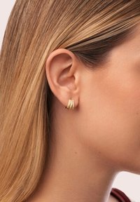 Gli orecchini a cerchio in oro presentano un design a più strati con scanalature orizzontali e piccole pietre incastonate per un dettaglio aggiuntivo.
