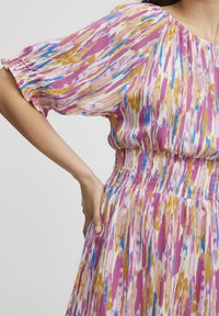 Rochie colorată cu mâneci scurte bufante, având un tipar vibrant în nuanțe de roz, albastru și galben. Talie încrețită și design cu fustă fluida.