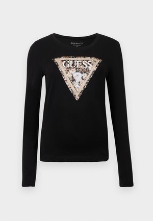 Melnas garām piedurknēm T-krekls no mīksta auduma ar lielu trīsstūra rakstu ar metāla apmali un stilizētu "GUESS" tekstu.