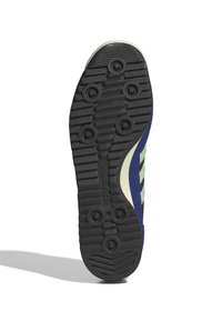 Talpă de pantof din cauciuc negru cu un model concentric și puncte de tracțiune circulare. Partea laterală prezintă țesătură bleumarin și dungi de accent verde.