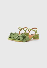Sandali in suede verde con un motivo floreale sulla punta, apertura sul retro e tacco a blocco. Le cinghie sono regolabili per una vestibilità sicura.