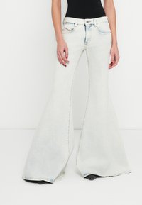 Heledasinised lehvikpüksid teksariidest, millel on kõrge vöökoht, kontrastsed õmblused ja laiad sääred, mis lähenevad põlvedelt allapoole.