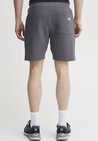 Gray waffle-patterned shorts with a back pocket. Made from textured material, featuring an elastic waistband and a relaxed fit.