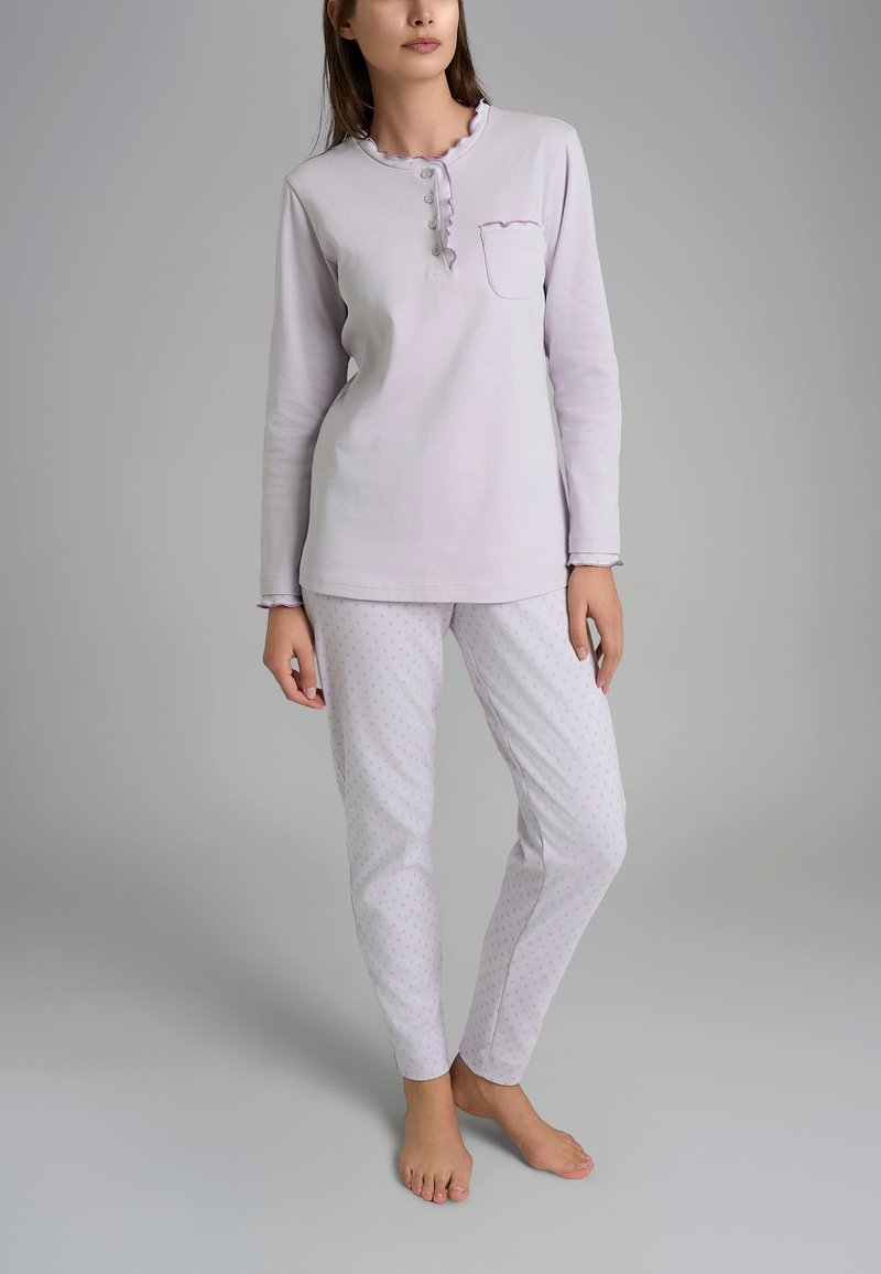 Top lungo manica di un leggero viola con bottone a pressione, scollatura a ondine. Pantaloni del pigiama bianchi con pois rosa. Tessuto morbido, vestibilità comoda.