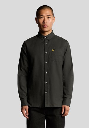 Chemise à manches longues vert foncé en coton, avec un col boutonné, une poche avant et un petit logo jaune sur la poitrine.