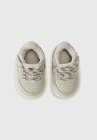 Jasno beżowe sneakersy z tęczowymi siateczkowymi sznurówkami, okrągłym nosem, perforowanymi detalami i subtelnym, wypukłym logo po bokach.