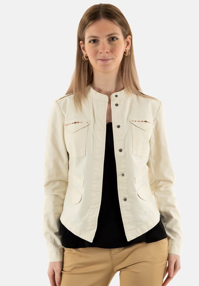 Giacca in denim color crema con colletto alto, chiusura anteriore a bottoni, due tasche sul petto e sottili dettagli ricamati lungo la spalla.