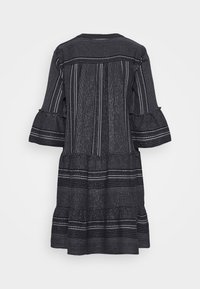 Robe noire et blanche à motifs, longueur genou, manches trois-quarts à volants et ourlet à étages, vue de dos.