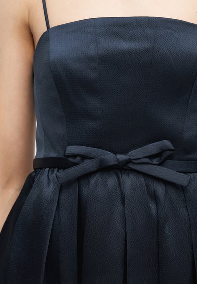 Μπλε-σκούρο φόρεμα χωρίς τιράντες με μια διακριτική υφή, με ζώνη στη μέση και φιόγκο δεμένο στο μπροστινό κέντρο.