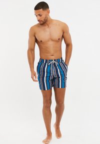 Bañador de rayas azules con cintura ajustable, que presenta rayas verticales en azul oscuro, azul claro y beige. Textura de tela suave.