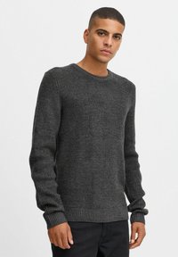 Dark gray ribbed knit sweater with a round neck, long sleeves, and textured fabric; features fitted cuffs and waistband.