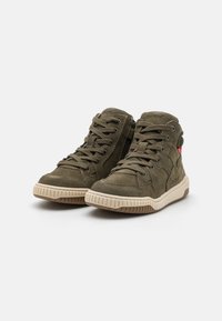 Zapatos altos de ante verde oliva con un collar acolchado, cierre de cordones negros, cremallera lateral y una suela de goma beige claro con ranuras.