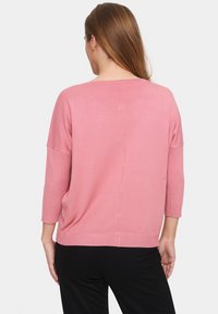 Pink, lightweight sweater with a relaxed fit, three-quarter sleeves, and ribbed hem. Features a center back seam and soft texture.