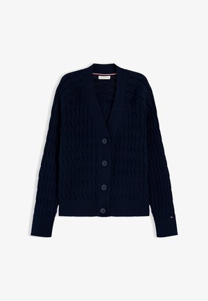 Marineblå kabelstrikket cardigan med V-hals, lange ermer, fire knapper foran, ribbestrikkede mansjetter og kant, lagt flatt på hvit bakgrunn.