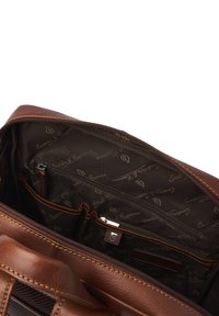 Bruine leren handtas met een gestructureerd oppervlak, voorzien van een ritssluiting en meerdere binnenvakken langs een patroon gevoerd interieur.