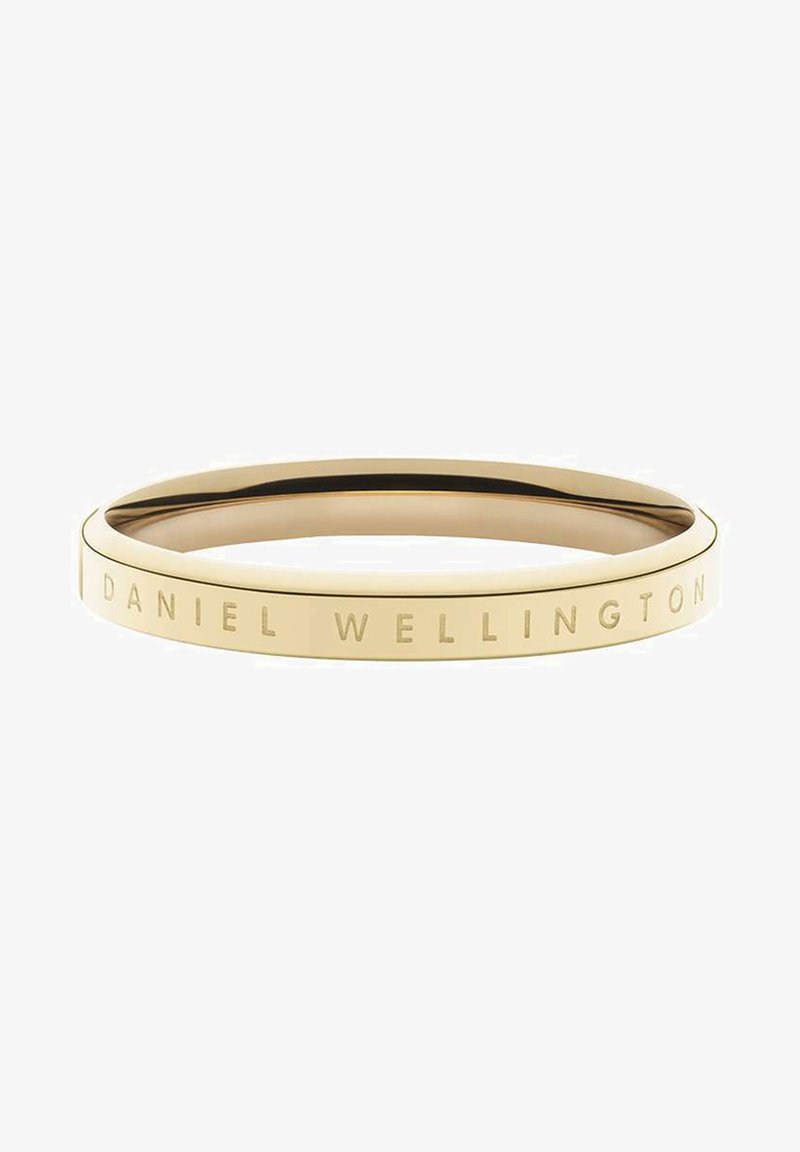 Bracciale dorato con una finitura liscia. Presenta il testo inciso "DANIEL WELLINGTON" attorno al suo bordo. Forma circolare, design minimal.