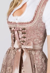 Dirndl-Kleid mit Spitzenbesatz in altrosa und floralen Mustern. Verfügt über ein tailliertes Oberteil, satinschimmernde Schnürbänder und einen voluminösen, strukturierten Rock.