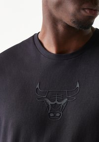 Μαύρο βαμβακερό t-shirt με ανάγλυφο μαύρο λογότυπο ταύρου στο στήθος. Λαιμόκοψη crew, κοντά μανίκια και ομαλή υφή.