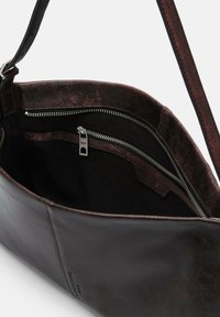 Borsa a spalla in pelle nera con una finitura metallica marrone all'interno. Presenta un compartimento con zip e una superficie liscia con cuciture robuste.