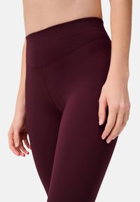 Bordeaux hoge taille legging made van een gladde, elastische stof, met een naadloos ontwerp en minimale stikdetails.