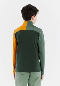 Pullover verde e arancione con zip a metà colletto alto, caratterizzato da una texture di tessuto misto e blocchi di colore a contrasto sul retro.