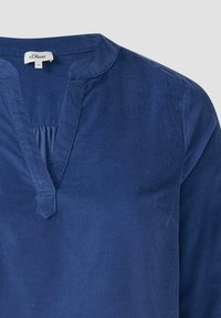 Blaue Cordbluse mit V-Ausschnitt, gefälteltem Detail und subtilen strukturierten Streifen. Etikett liest "s.Oliver", Größe 44.