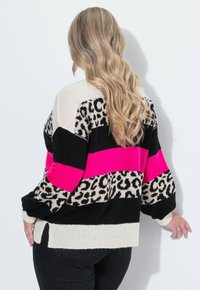 Pletený svetr v černé, krémové a jasně růžové s leopardím potiskem. Má oversized střih, žebrované manžety a boční rozparky na lemu.