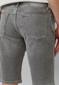 Grijze denim shorts met een rechte snit, voorzien van achterzakken en contrasterende stiksels. De stof heeft een gladde, licht vervaagde textuur.