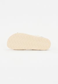 Rubberen zool met een golvend patroon, beige kleur. Glad bovenoppervlak met een minimalistisch ontwerp en lichte tint. Vlak profiel, geschikt voor casual dragen.