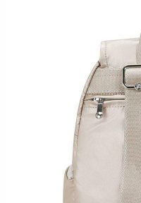 Sac à dos beige avec une texture lisse et brillante, doté d'une poche zippée et d'un accent en métal argenté sur la sangle.