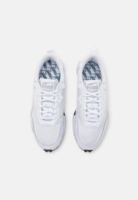 Chaussures de sport blanches en mesh et matériau synthétique, avec une semelle texturée, un design à lacets et une semelle intérieure à motif avec le détail du logo.