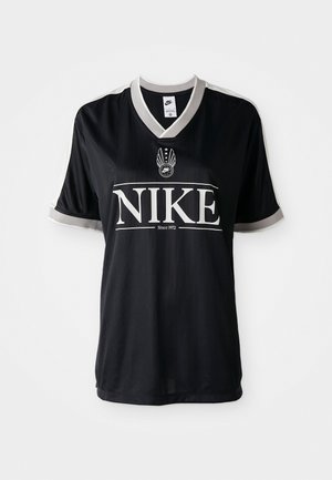 Svart Nike-drakt med korte ermer, V-hals og grå detaljer. Har stor hvit "NIKE" -logo og emblem med vinger på brystet.
