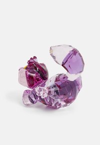 Klar kristallfigur av en hund i olika nyanser av lila, med facetter, rundade former och en liten detaljerad guldkoppel.