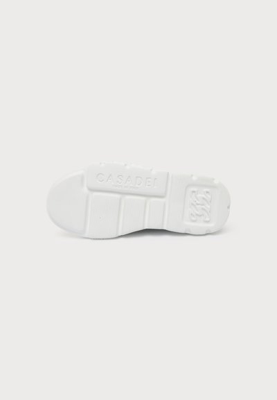 Semelle de chaussure en caoutchouc blanc avec motifs d’adhérence texturés et "CASADEI Made in Italy" embossé au centre.