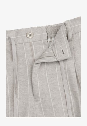 Lysegrå bukser med nålestriber, knaplukning, lynlås og bæltestropper, med delvist åben taljeområde.