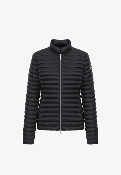 Doudoune matelassée noire avec fermeture éclair intégrale à l'avant, col montant, manches longues et un écusson rond avec logo sur le bras gauche supérieur.