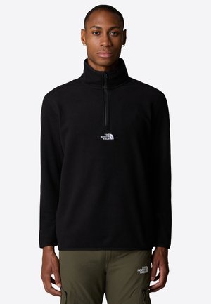 Pullover de forro negro con cuello alto y cierre frontal de media cremallera. Presenta un logo blanco en el pecho. Material texturizado con mangas largas.
