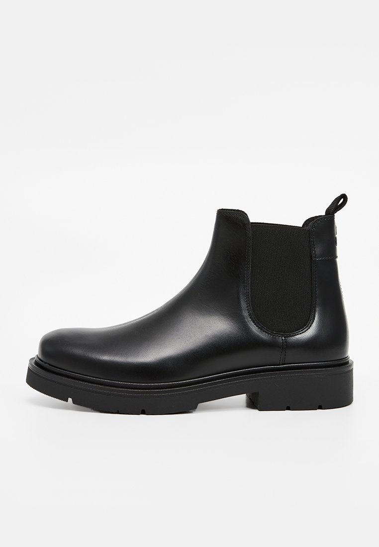 Bottines Chelsea en cuir noir avec des panneaux latéraux élastiques, bout arrondi et semelle en caoutchouc épaisse. Languette au talon pour un enfilage facile.