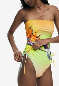 Costum de baie tip maiou fără bretele, cu un design degradat de la galben la verde, decorat cu imprimeu cu păsări tropicale, cu șnururi ajustabile pe lateral și textură netedă.