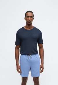 Camiseta de manga curta azul-marinho com padrão texturizado e decote redondo, combinada com calções azuis claros com cordão para um visual casual.