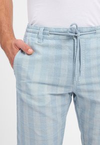 Light blue plaid trousers made of woven fabric, featuring a drawstring waistband and side pockets for added comfort.