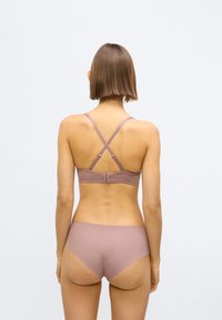 Let lyslilla bh og matchende trusser lavet af glat, elastisk stof. Bh'en har krydsede stropper på bagsiden og en hægtepåsætning.