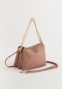 Pink leather handbag with a textured finish, gold chain handle, and detachable strap. Features a zip closure and folds for added design.